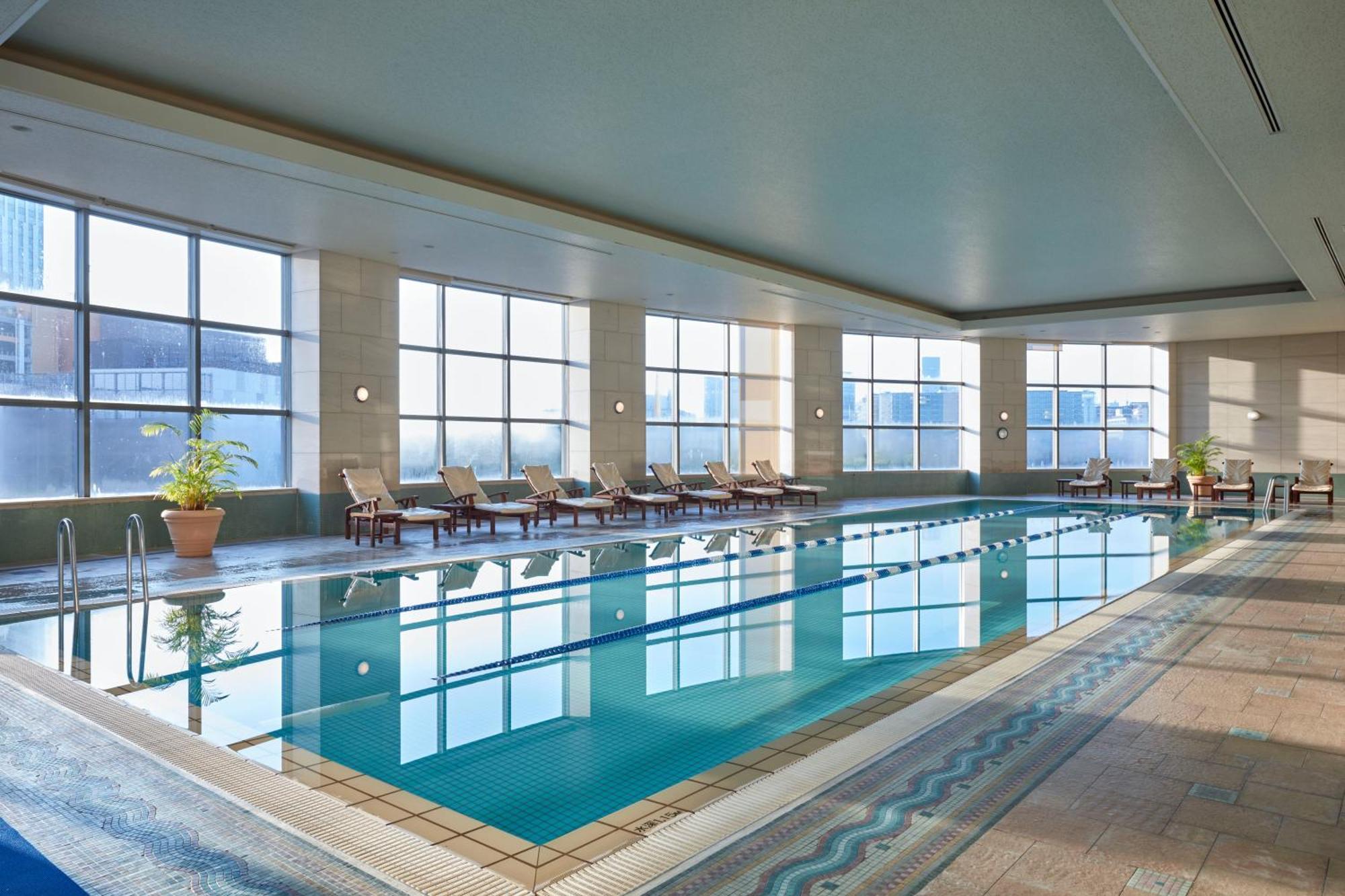 Grand Nikko Tokyo Daiba Hotel Exterior photo The image shows an indoor swimming pool area. The pool is rectangular and features clear blue water that reflects the light. Alongside the pool, there are several lounge chairs positioned for relaxation. Large windows allow ample natural light to flo